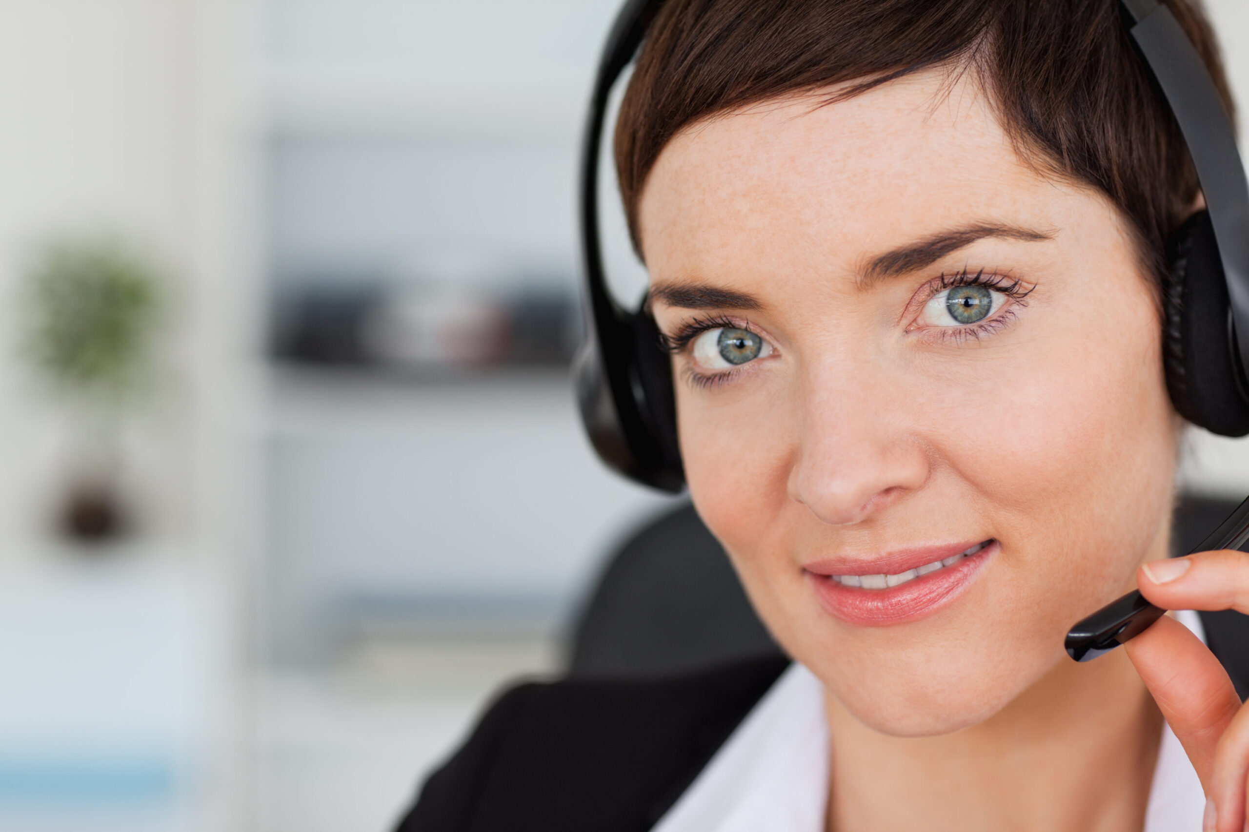 Close up of a cute secretary calling with a headset in her office