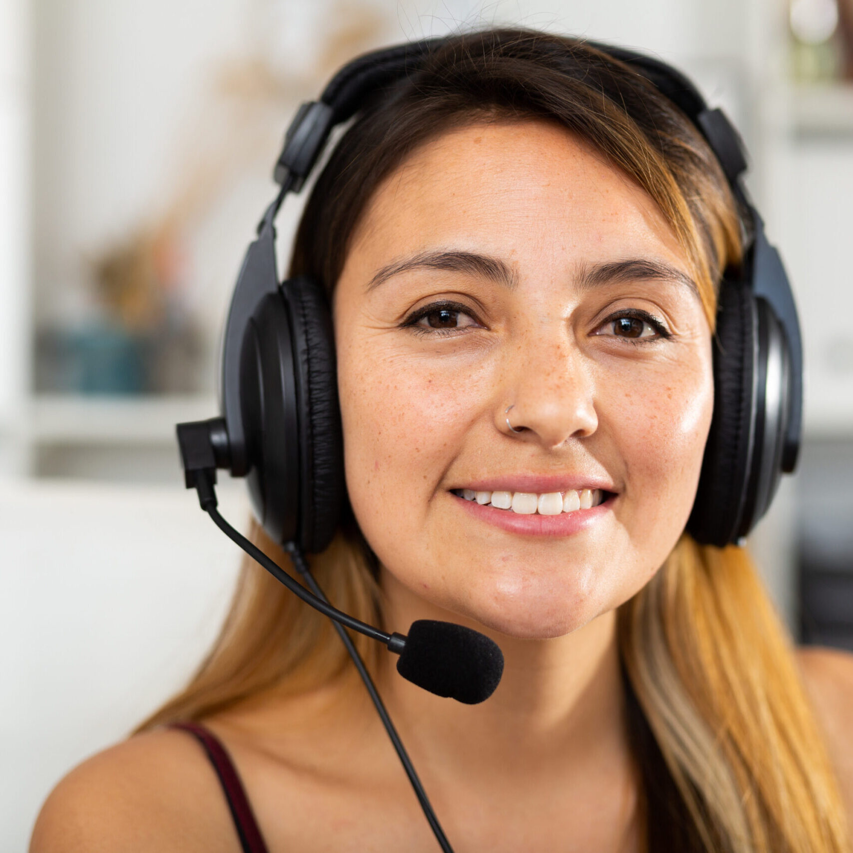 Portrait of young smiling latina woman with headset at call center office